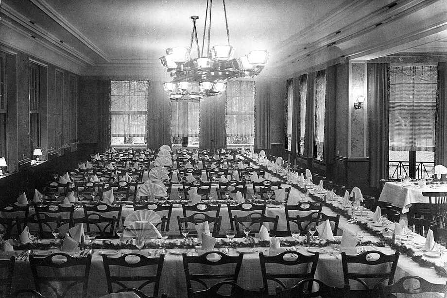 schwarz-weiss Foto des damaligen Bankettsaals mit feierlich gedeckten langen Tafeln