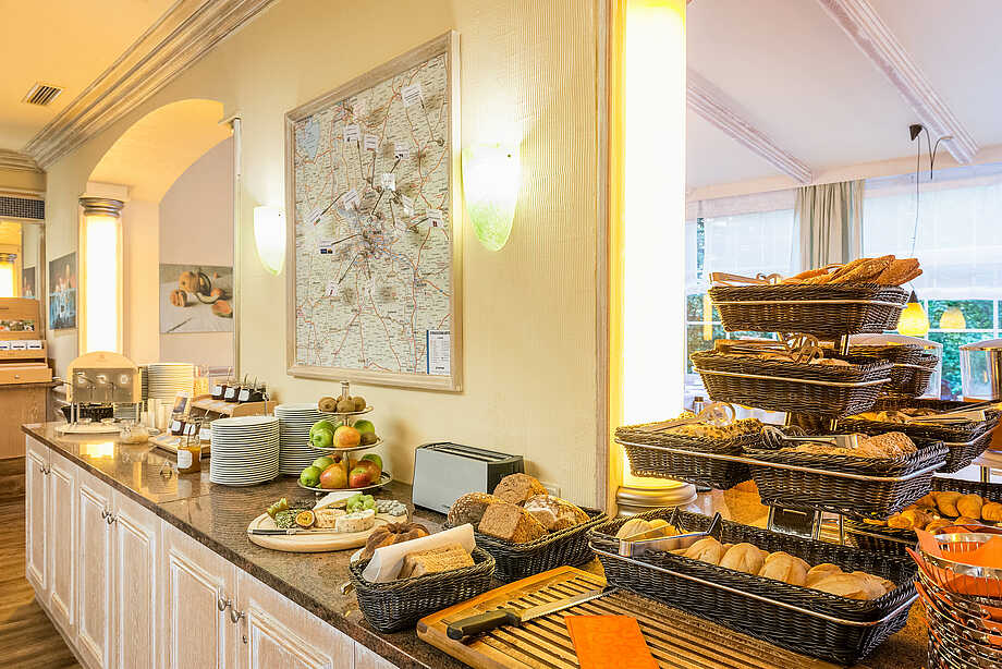 Blick auf das Frühstücksbuffet mit Brot- und Brötchenauswahl, Kuchen, Käseauswahl, Obstetagere, Konfitüren und Honig
