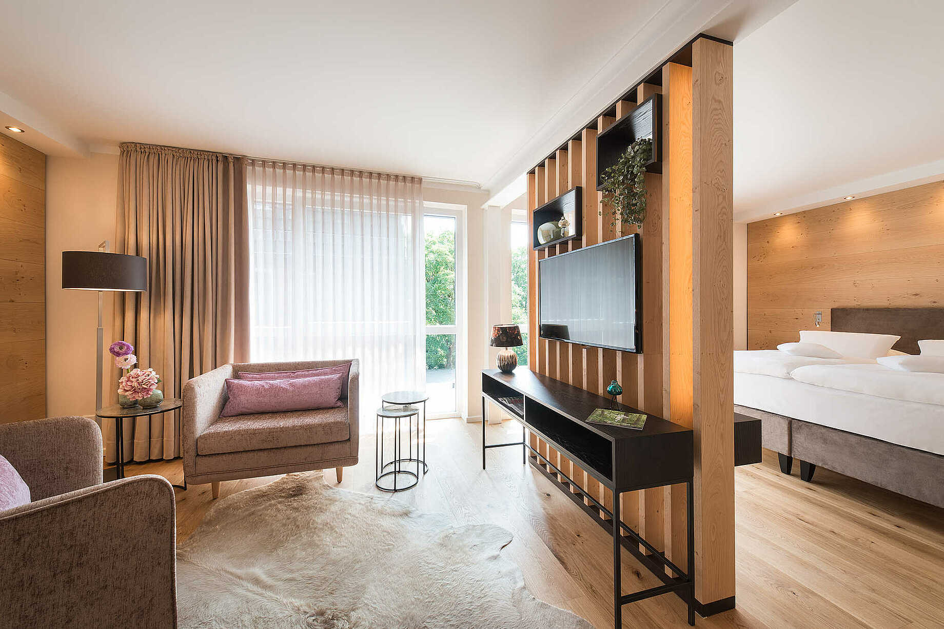 Wohnbereich mit zwei Sesseln und einem Flachbild-TV über einem Sideboard - Atmosphäre in Holz