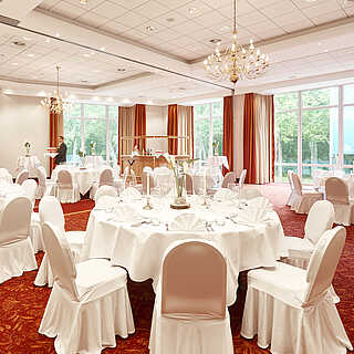 Veranstaltungssal mit eingedeckten rudnen Tischen und Stühlen mit weißen Hussen für eine Hochzeitsfeier im Hotel Munte am Stadtwald