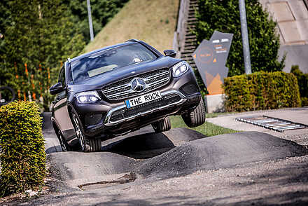 schwarzer Mercedes Geländewagen fährt über einen Hügel im Parcour