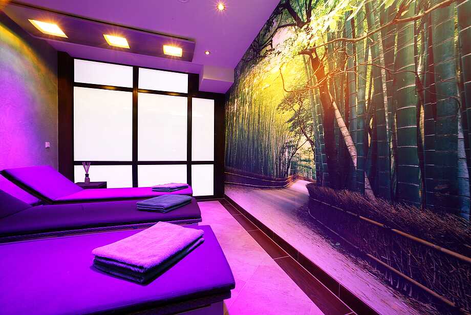 Klafs Sonnenraum im Wellnessbereich mit gemütlichen Liegen und Blick auf ein Wandbild mit Bambuswald