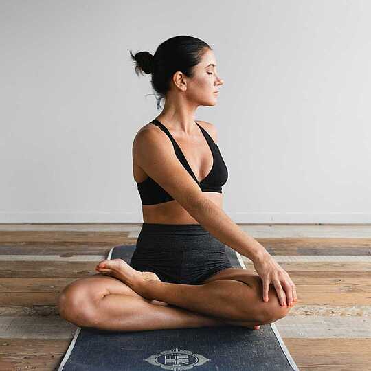 Pilates-Wochenende Frau sitzt in Yoga-Pose auf einer Sportmatte