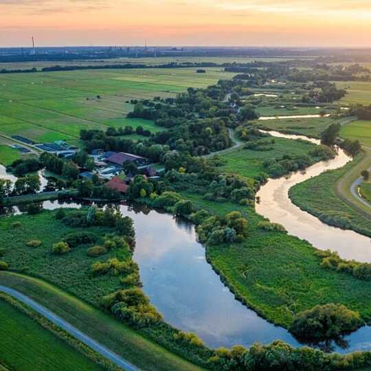Grüne Wiesen mit Fluß und Feldweg bei Sonnenaufgang