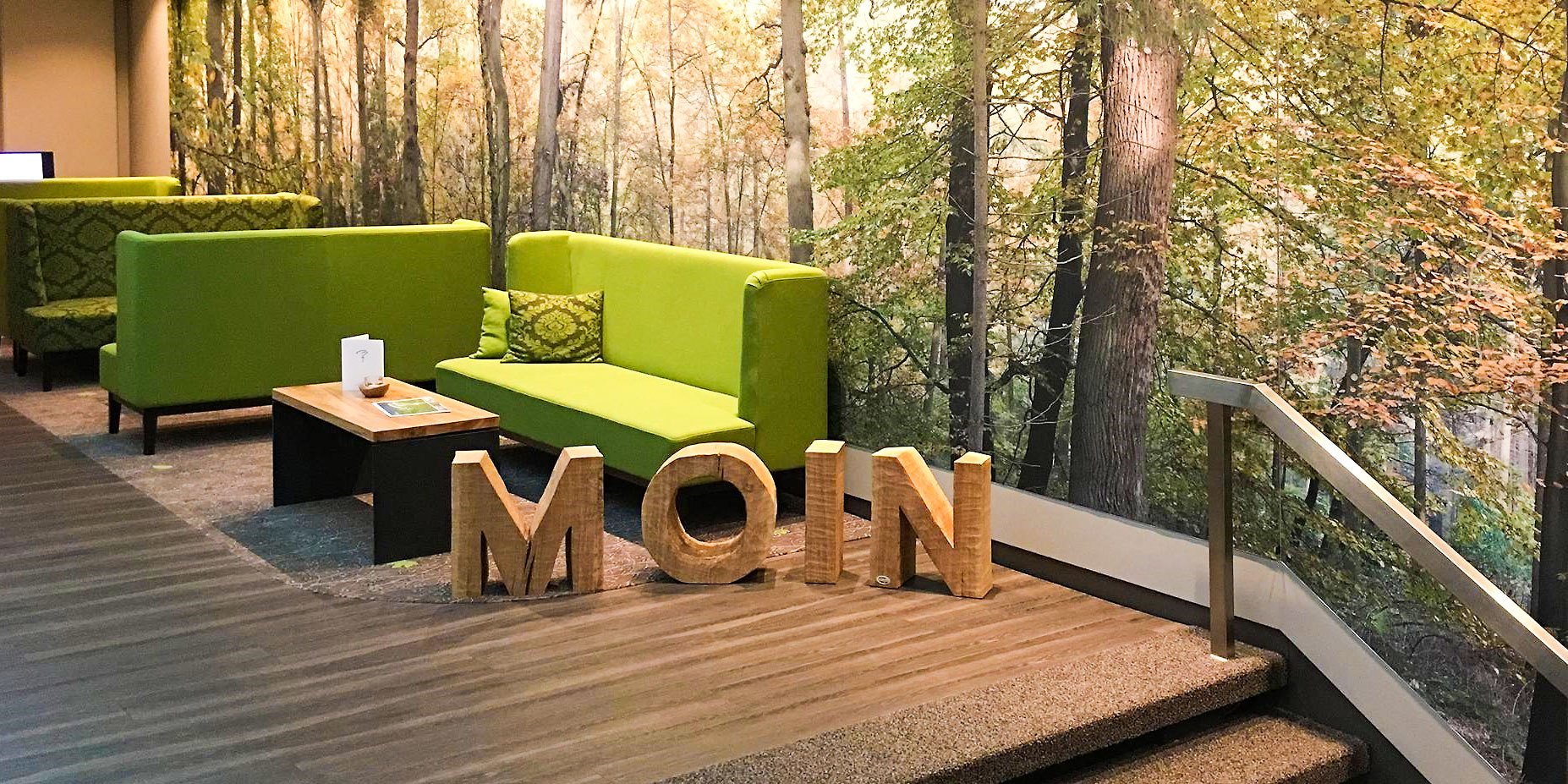 "Moin" Schriftzug in Holz in der Lobby mit Sofas im Hintergrund