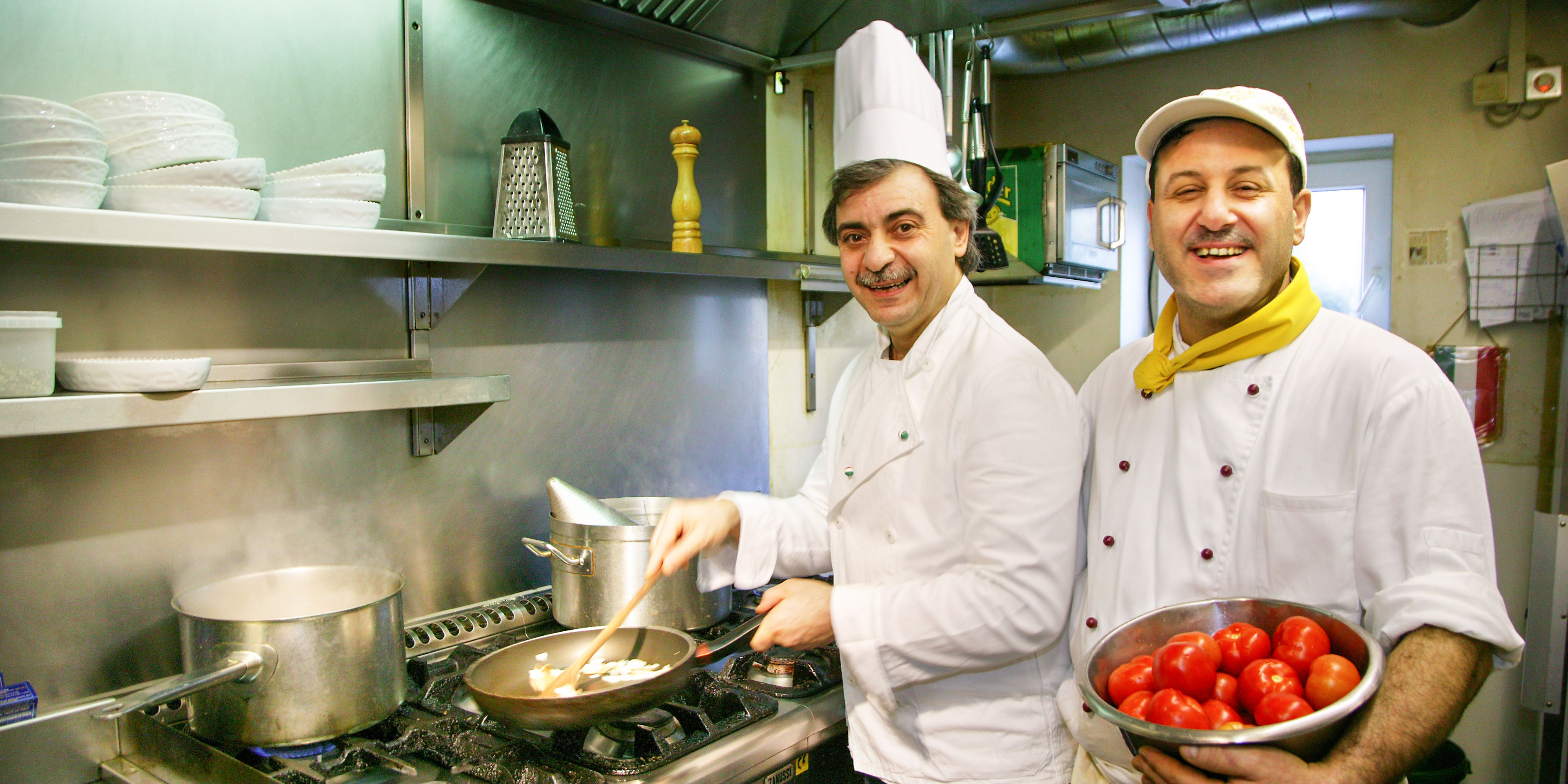 Zwei Männer in weißem Küchenoutfit kochen